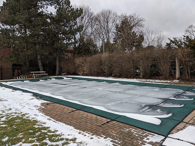 Swimming pool cover with some snow on it.