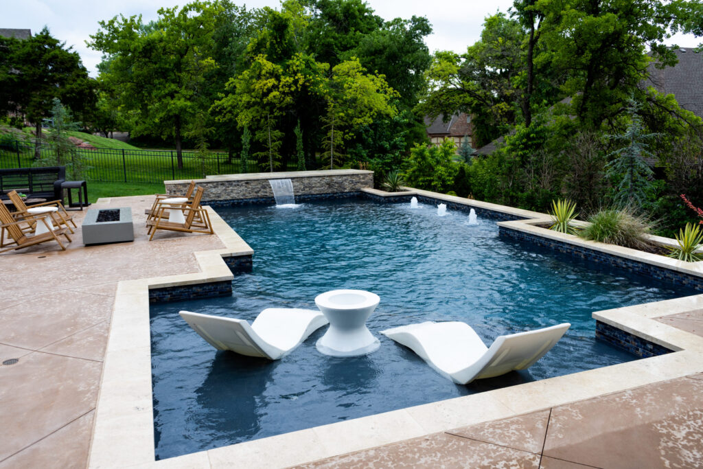 an inground swimming pool with two white chairs sitting on a sun shelf. the pool has a midnight blue aquabright coating from ecofinish
