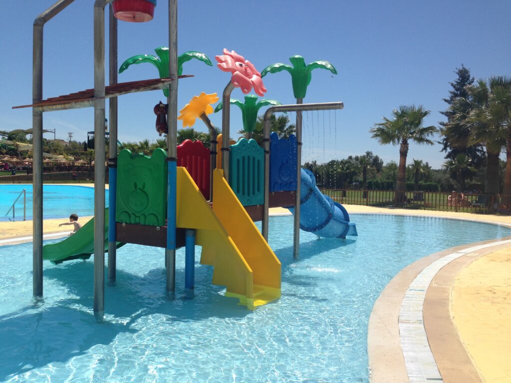Children's aquatic playground with interactive features linked to a nearby shallow pool.