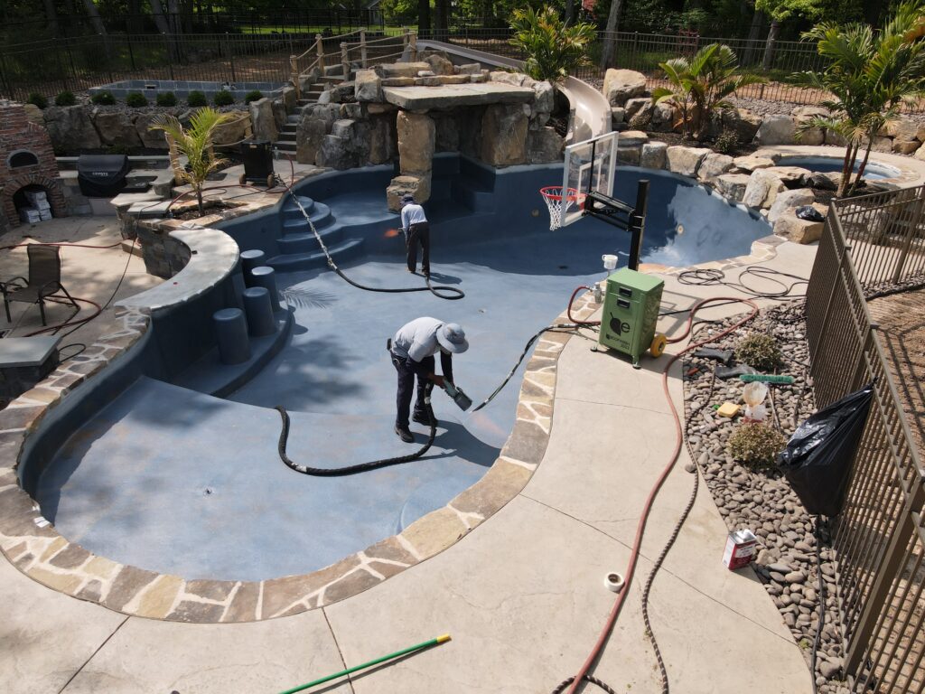 Workers using controlled flames for surface treatment on an in-ground pool.