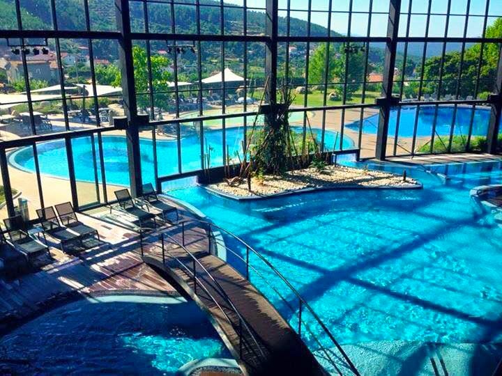 Indoor and outdoor pools, both adorned in stunning shades of blue, divided by a vast glass window.