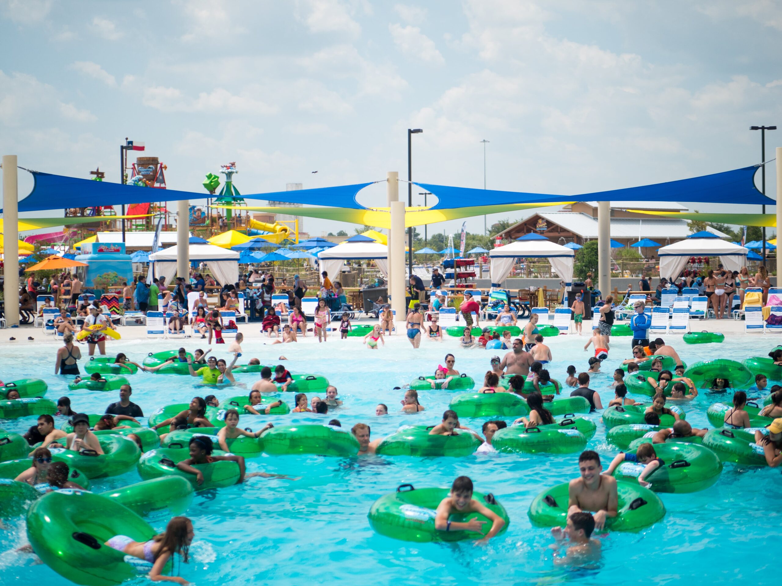 A crowded pool filled with swimmers and their green inflatable tubes.