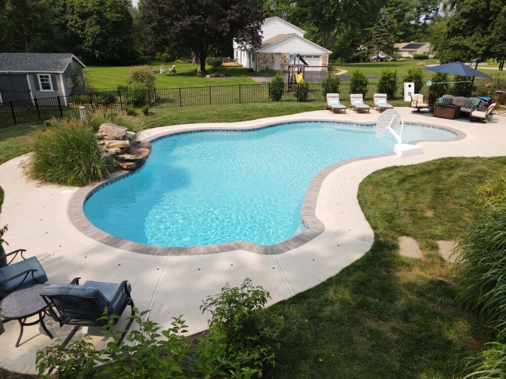 Scenic view of a free-form inground pool in a beautiful backyard on a sunny day.