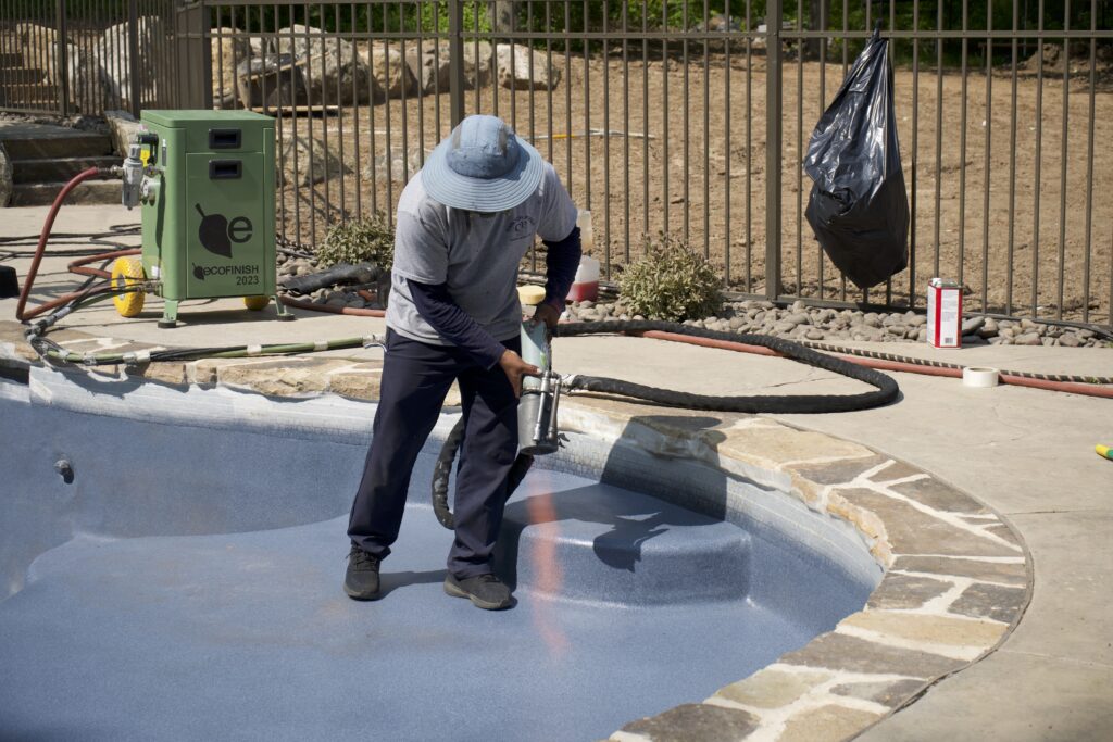 Surface treatment of an unoccupied in-ground pool being carried out with a weed burner.